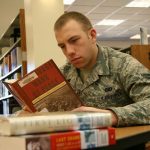 a man in an army uniform reads a book in a library