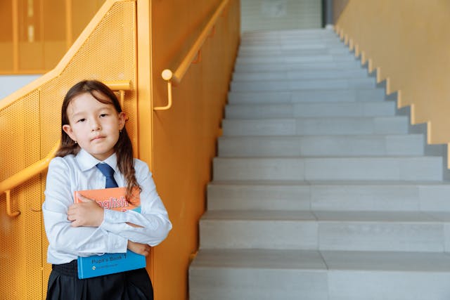 A girl in a school uniform standing by stairs