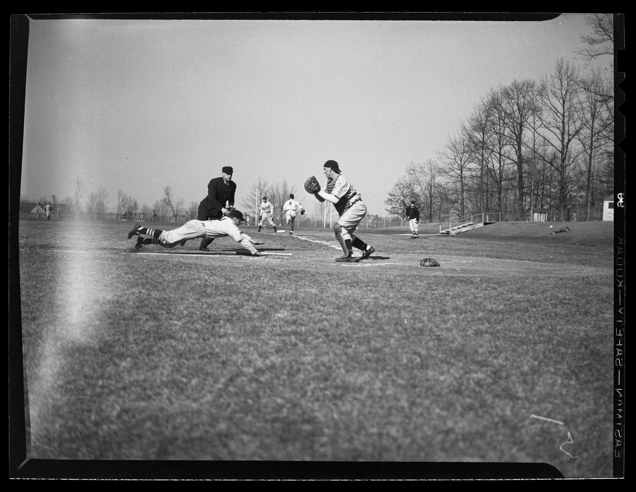 A baseball playing diving for a base with the baseman getting ready to tag him.
