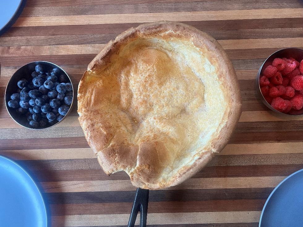  A German pancake in a cast-iron pan with berries on a table