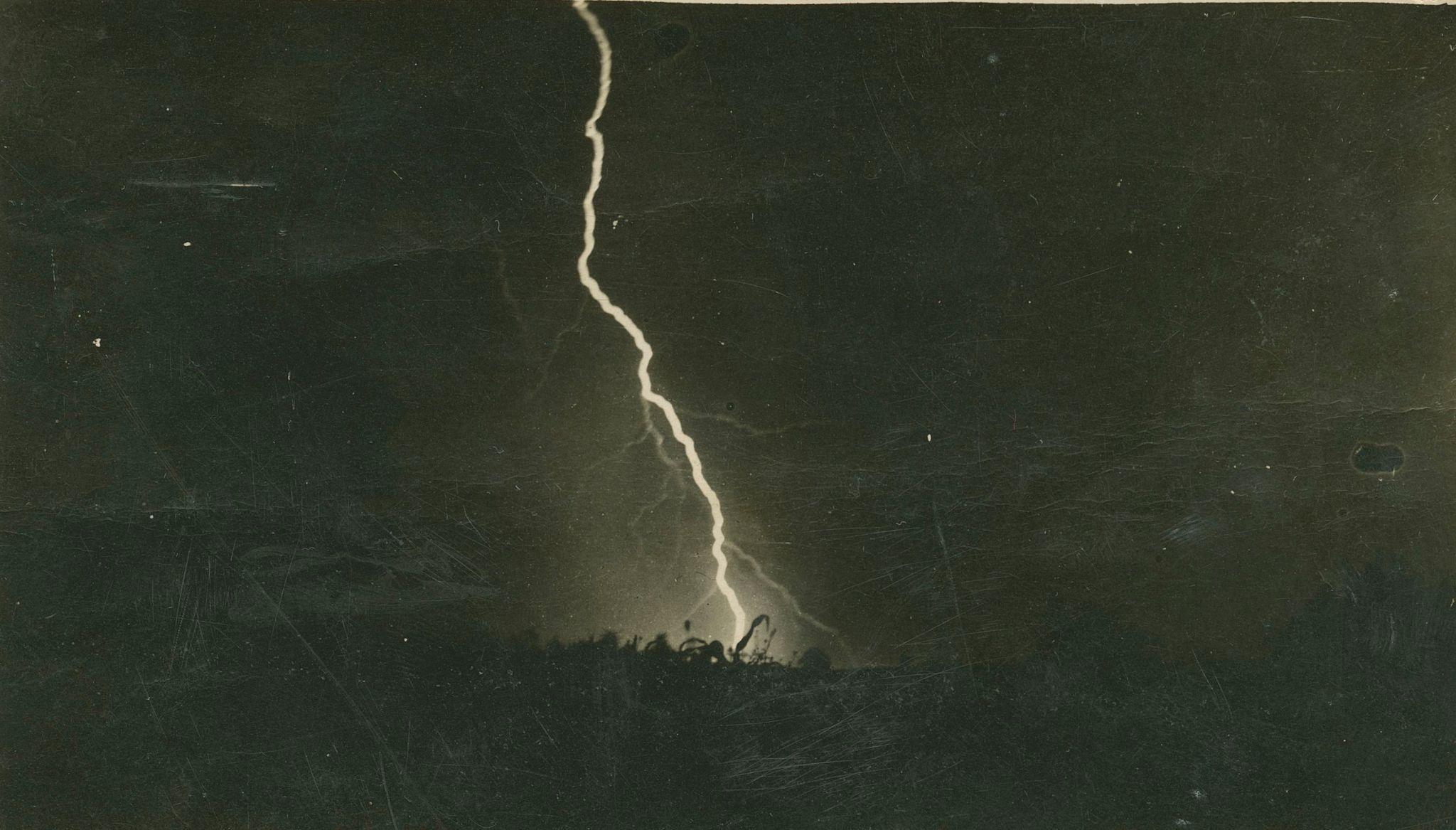 A lightning strike down the middle of the image strikes the ground. 