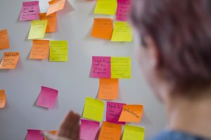 man staring at rows of post-it notes on the wall