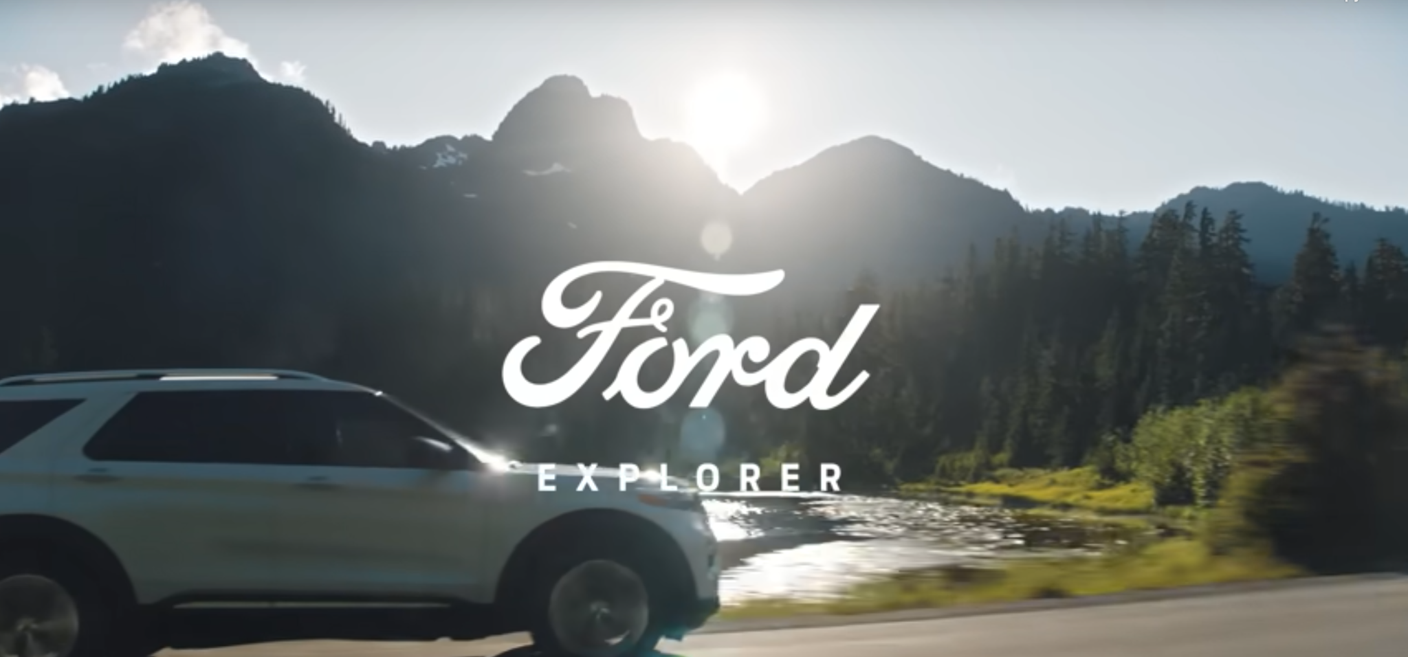 A Ford Explorer and accompanying logo in front of an expanse of mountains.