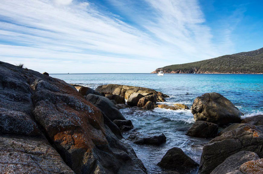 Image of a rocky coastal scene with a boat in the distance.