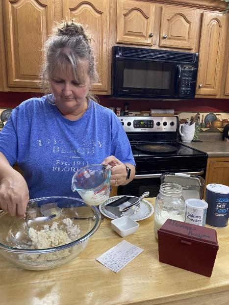 My mom pouring milk into the rest of the biscuit dough mixture.