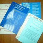 print editions of journals in the economics discipline on a desk stacked on a desk