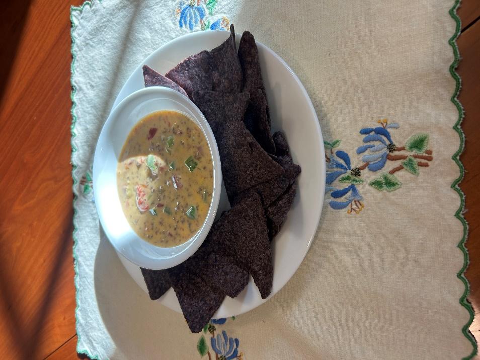 A bowl of Rotel dip on a plate of tortilla chips 
