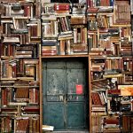 a small metal door surrounded by bookcases stuffed with books