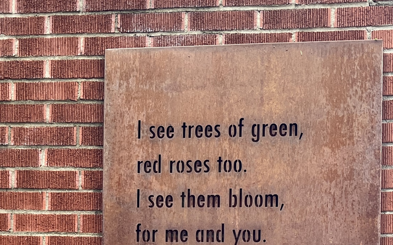 This image is a photograph of a plaque on the Louis Armstrong House Museum garden wall.The image depicts the first lines of "What a Wonderful World" by the Jazz musician Louis Armstrong