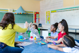 A teacher works with students at a table