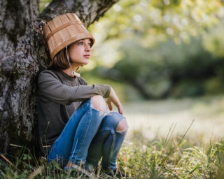 A girl by a tree with a bucket on her head